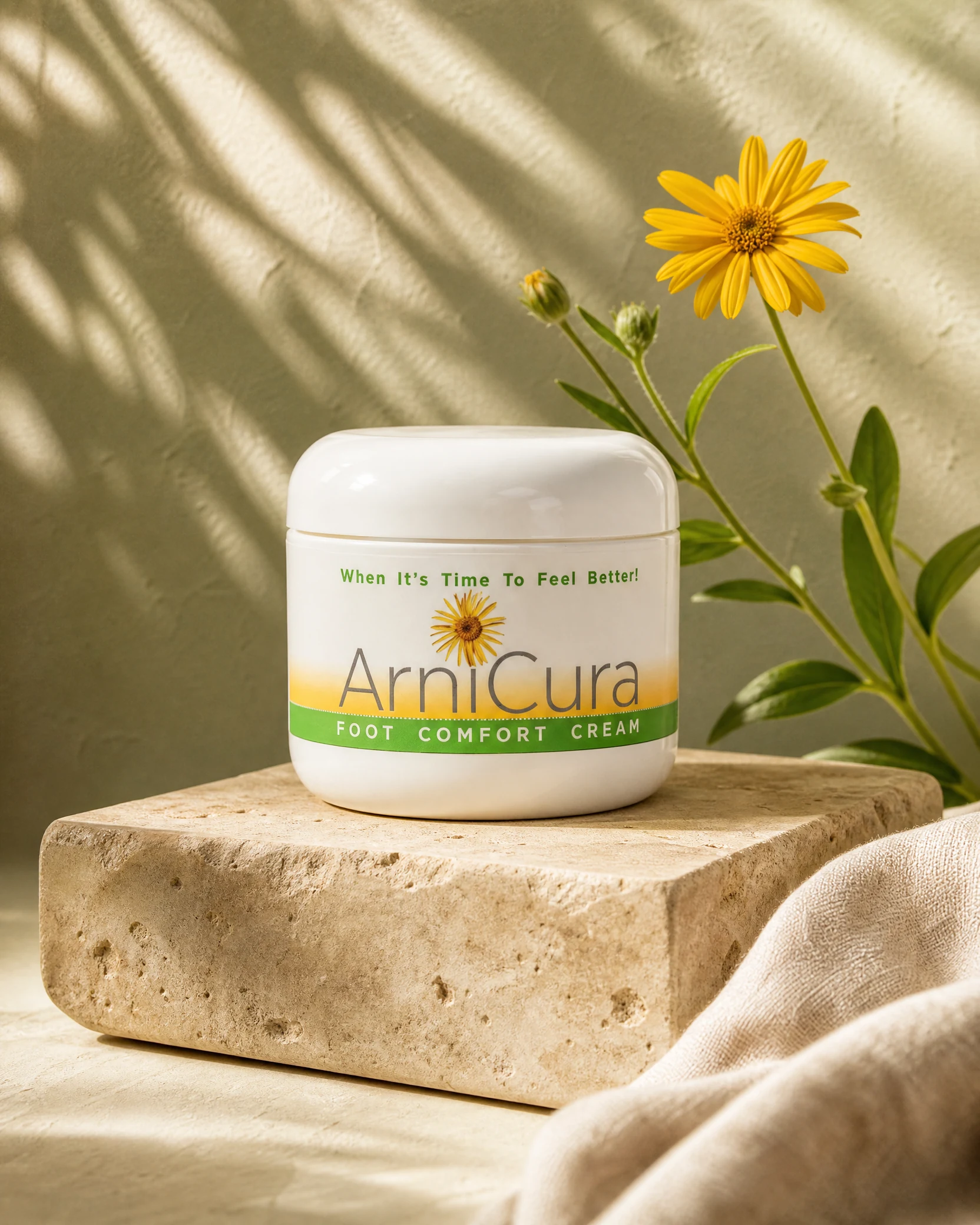 ArniCura Foot Comfort Cream jar on warm limestone beside a yellow arnica flower